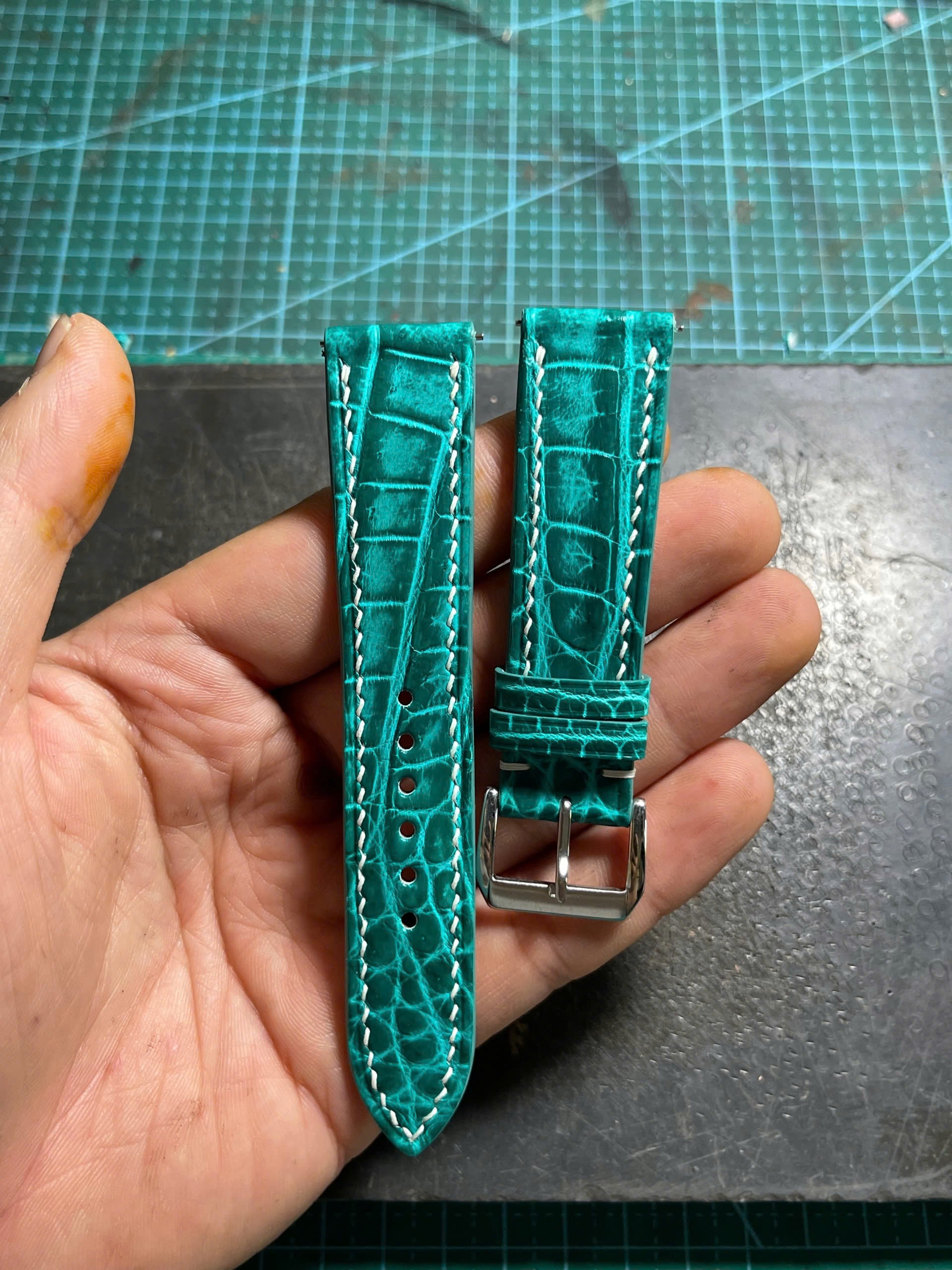 The completed two-piece watch strap held in hand for final inspection